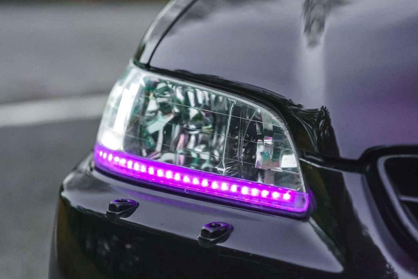 custom Car headlight with purple LED strip on a blurred background